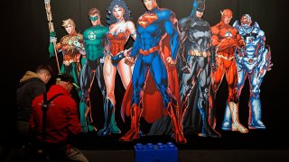 In this April 26, 2018, file photo, a DC Comics universe poster of Batman, Superman, Wonder Woman, The Joker, The Flash and others is displayed during the press preview of the exhibition "The Art of the Brick: DC Super Heroes" at Parc de la Villette in Paris, France.