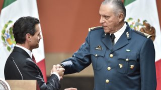 Mexican President Enrique Pena Nieto (L) congratulates Defense Secretary Gral. Salvador Cienfuegos Zepeda after his speech about recaptured drug baron Joaquin Guzman Loera, AKA "El Chapo", in Mexico City on January 8, 2016. Mexican marines recaptured fugitive drug kingpin Joaquin "El Chapo" Guzman on Friday in the northwest of the country, six months after his spectacular prison break embarrassed authorities.