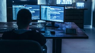 Man sits looking at computer screens