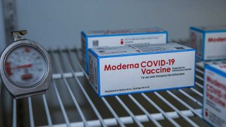 Boxes containing the Moderna COVID-19 vaccine sit in a freezer