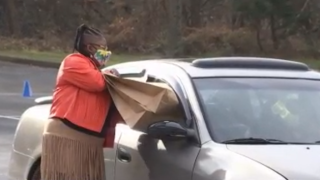 Woman pushes bag into car through window for a coat drive