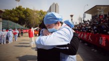 A medical worker, right, hugs a member of a medical assistance team from Jiangsu at a ceremony marking their departure after helping with the COVID-19 coronavirus recovery effort, in Wuhan, China, March 19, 2020.