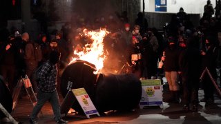 A trash can burns as people take part in a protest against police brutality, late Sunday, Jan. 24, 2021, in downtown Tacoma, Wash., south of Seattle. The protest came a day after at least two people were injured when a Tacoma Police officer responding to a report of a street race drove his car through a crowd of pedestrians that had gathered around him. Several people were knocked to the ground and at least one person was run over.