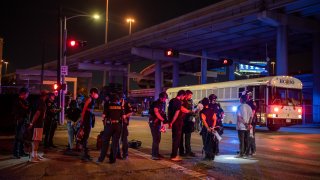 A group of people being placed under arrest stand by a Harris County Jail bus after protesters were apprehended in a fenced in area on June 2, 2020 in Houston, Texas.