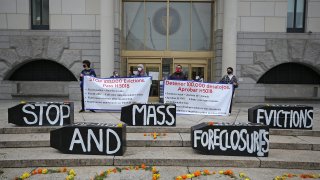 Demonstrators display signs calling for an end to evictions and foreclosures during a rally at Boston Housing Court outside the Edward W. Brooke Courthouse in Boston on Oct. 29, 2020.