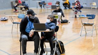 In this Jan. 19, 2021, file photo, Jordan Rodriguez, director of the Mulberry Street location of the Olivet Boys and Girls Club in Reading, works with Santana Sanford, a second grade student, as he does his school work on a laptop computer.