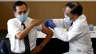 In this Feb. 17, 2021, file photo, Tokyo Medical Center director Kazuhiro Araki, left, receives a dose of COVID-19 vaccine in Tokyo.
