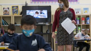 A teacher wearing a protective mask walks around the classroom during a lesson at an elementary school in San Francisco, California, U.S., on Monday, Oct. 5, 2020.