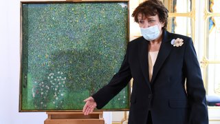 French Culture Roselyne Bachelot gestures as she stays next to a oil painting by Gustav Klimt painted between in 1905 called "Rosebushes under the Trees," during a ceremony at the Orsay museum in Paris, Monday, March 15, 2021. The French government hands over a Klimt painting to the grandchildren of the holocaust victim Nora Stiasny stolen by the Nazis during World War II.