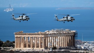 Military helicopters fly over Acropolis Hill during a military parade in Athens