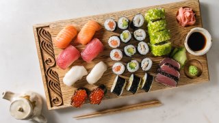 Sushi Set nigiri and sushi rolls on wooden serving board with soy sauce. chopsticks. ceramic teapot over white marble background. Flat lay. space. Japan menu