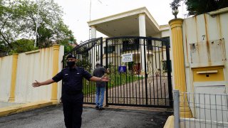 A staff member locks the front gate of the North Korean embassy in Kuala Lumpur, March 21, 2021.