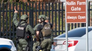 Members of the Frederick Police Department Special Response Team prepare to enter Fort Detrick at the Nallin Farm Gate in a convoy of vans and sedans following a shooting in Riverside Tech Park, near the Royal Farms on Monocacy Boulevard, Tuesday, April 6, 2021, in northeast Frederick, Md. Authorities say a Navy medic shot and critically wounded two people at a Maryland business park before fleeing to the Fort Detrick Army base, where he was shot and killed.
