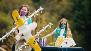 Girl Scouts Alice, right, and Gracie pose with a Wing delivery drone in Christiansburg, Va.