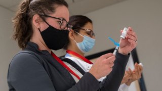 People prepare Covid-19 vaccines at an old TJ Maxx store