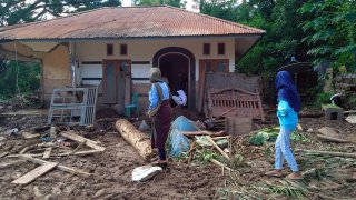 Indonesian women walk past a house damaged by flood in Waiwerang, on Adonara Island, East Nusa Tenggara province, Indonesia, Tuesday, April 6, 2021. Rescuers in remote eastern Indonesia were digging through the debris of a landslide Tuesday in search of people believed to be buried in one of several disasters brought on by severe weather in the Southeast Asian nation and neighboring East Timor.