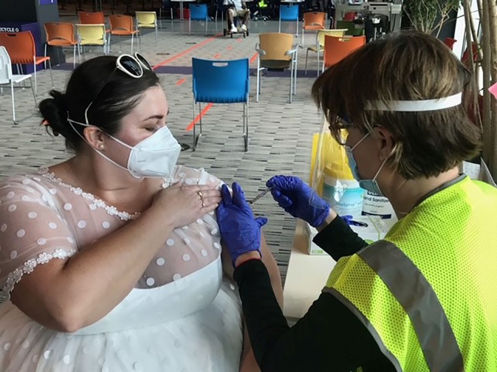 Sarah Studley gets a vaccination wearing the gown she planned to wear to her wedding reception.