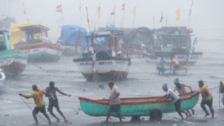 Fishermen try to move a fishing boat to a safer ground on the Arabian Sea coast in Mumbai, India, Monday, May 17, 2021. Cyclone Tauktae, roaring in the Arabian Sea was moving toward India's western coast on Monday as authorities tried to evacuate hundreds of thousands of people and suspended COVID-19 vaccinations in one state.