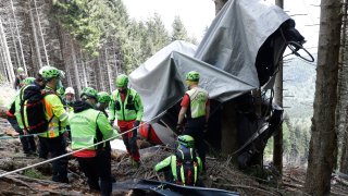 Rescuers search for evidence in the wreckage of a cable car after it collapsed near the summit of the Stresa-Mottarone line in the Piedmont region, northern Italy, Wednesday, May 26, 2021. Police have made three arrests in the cable car disaster that killed 14 people after an investigation showed a clamp, placed on the brake as a patchwork repair effort, prevented the brake from engaging after the lead cable snapped.