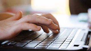 A child's hands typing on a computer laptop keyboard