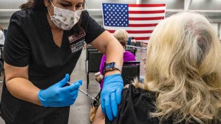 A woman gives a senior citizen a coronavirus disease (COVID-19) vaccine.