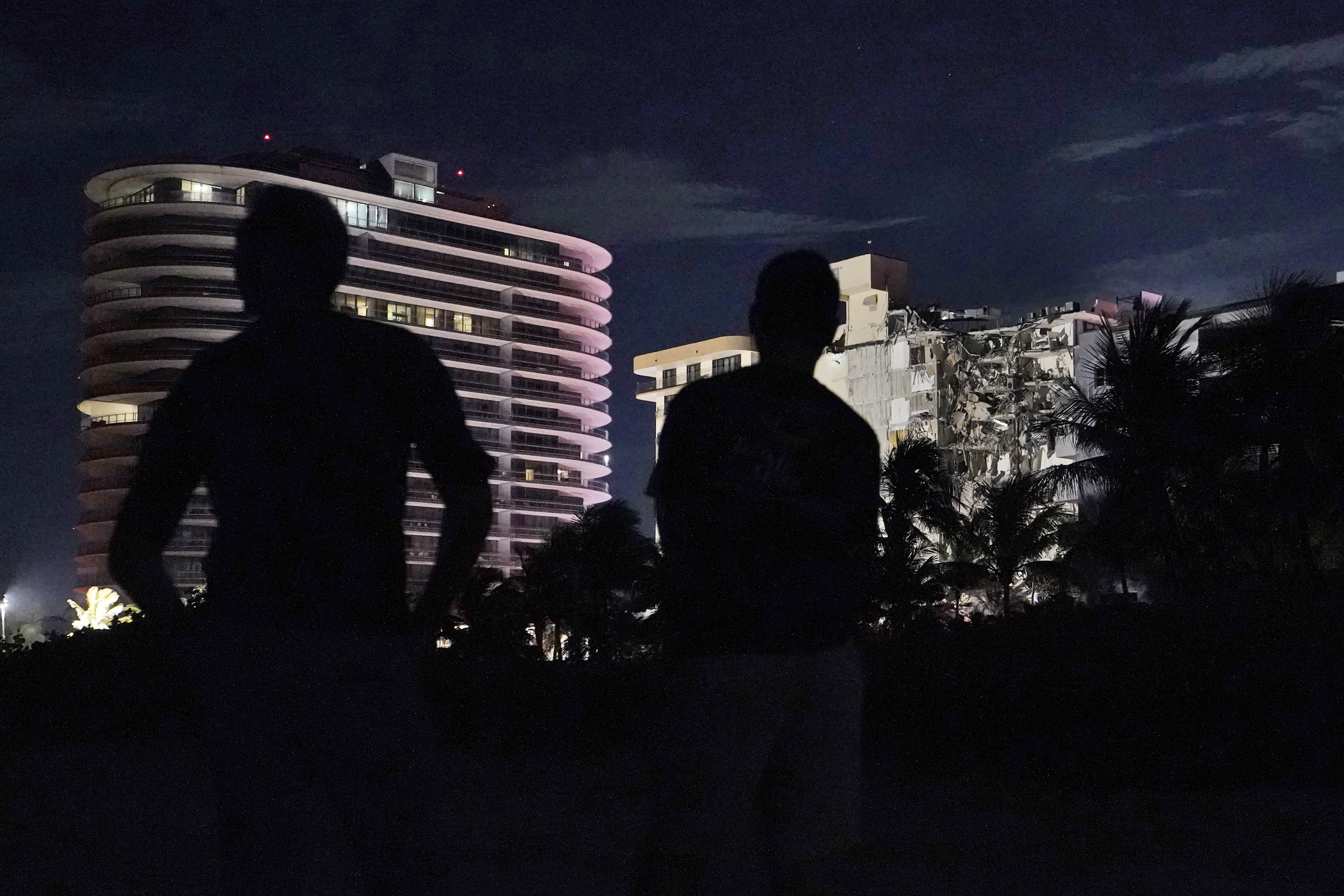 Bystanders look at a partially collapsed building early Thursday, morning June 24, 2021, in the Surfside area of Miami, Florida. A partial building collapse in Miami caused a massive response early Thursday from Miami Dade Fire Rescue, according to a tweet from the department’s account.