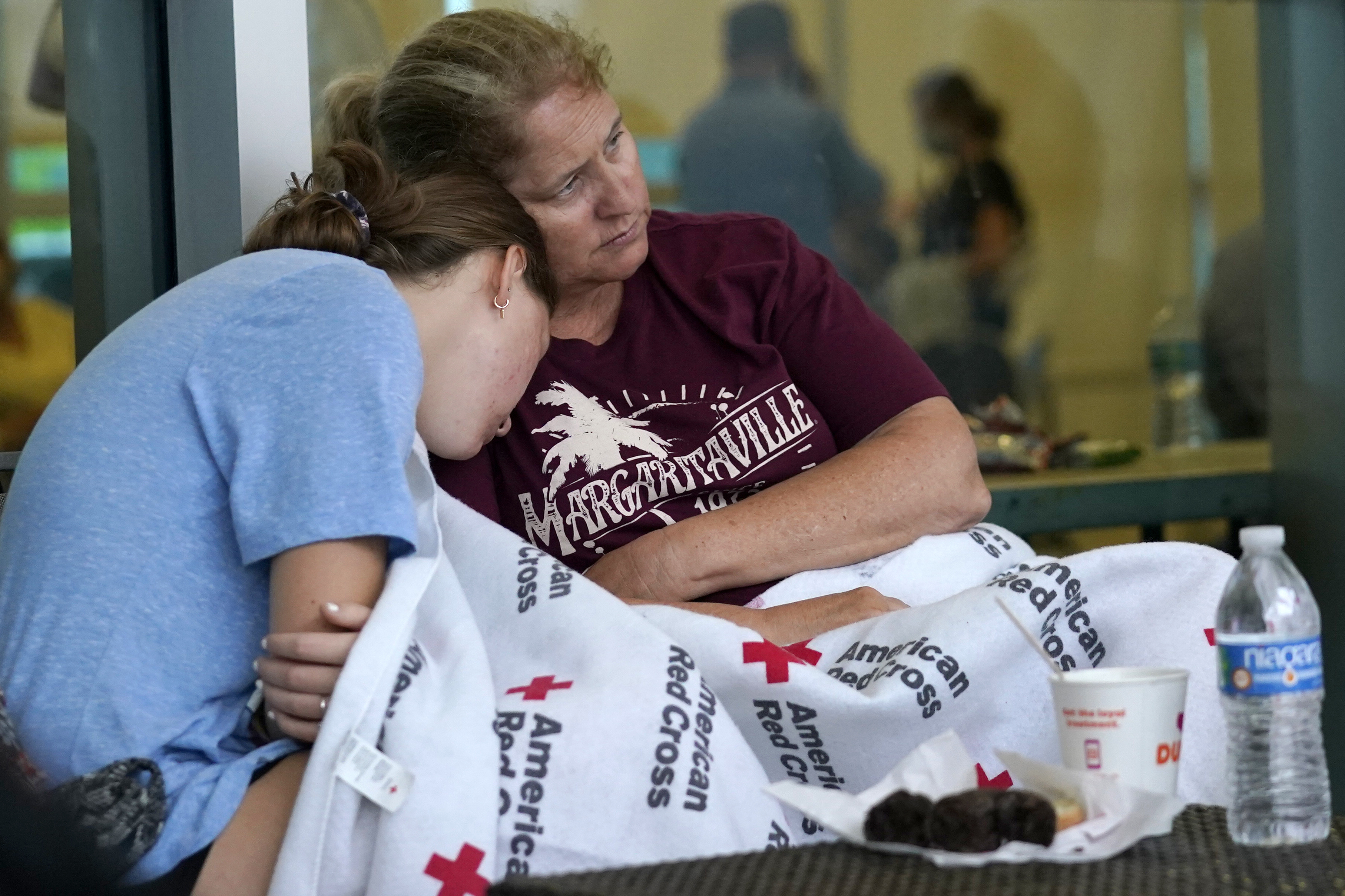 Jennifer Carr, right, sits with her daughter as they wait for news at a family reunification center, after a wing of a 12-story beachfront condo building collapsed, Thursday, June 24, 2021, in the Surfside area of Miami. Carr and her family were evacuated from a nearby building.