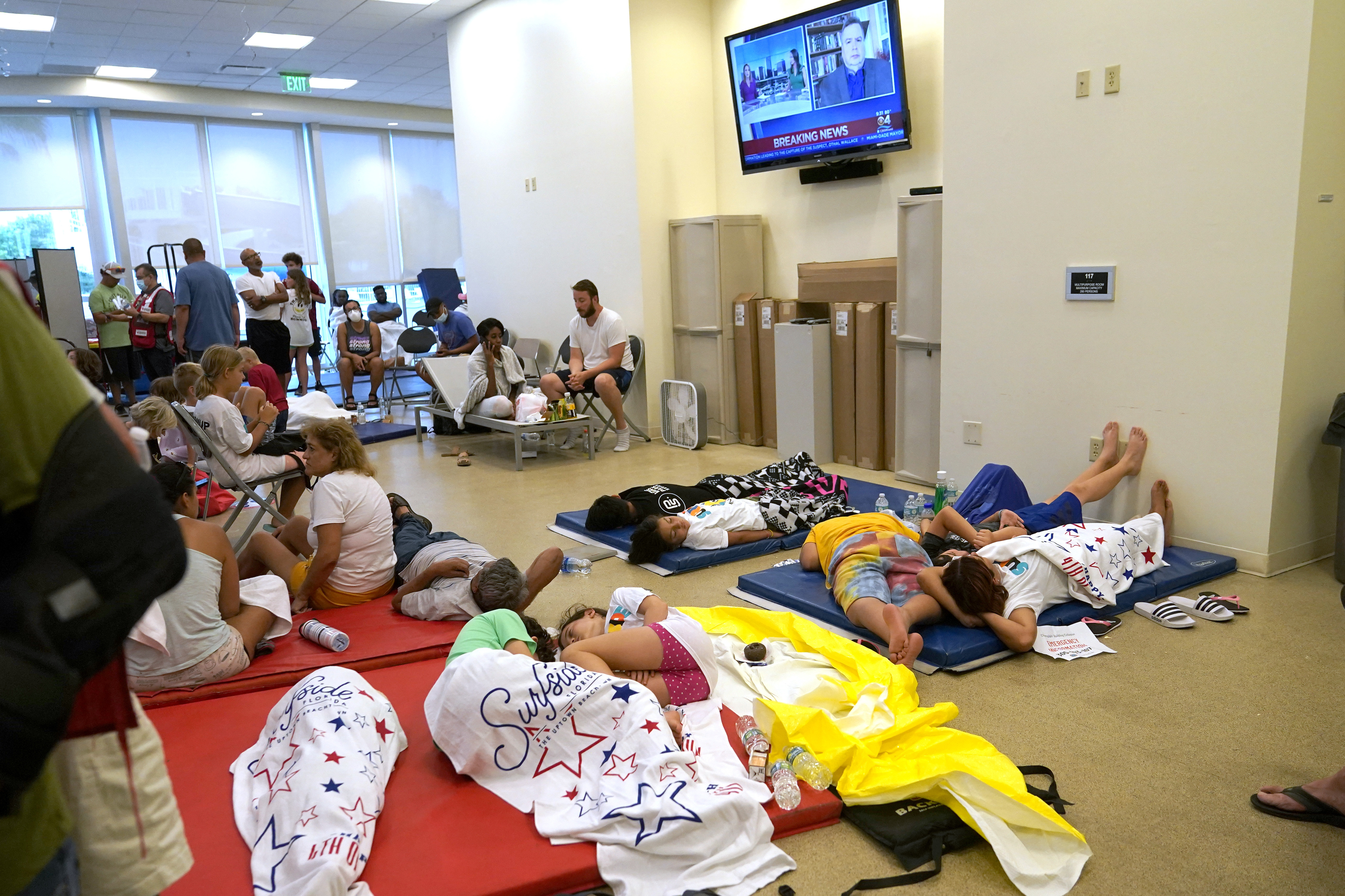 People lie on cots as they wait for news at a family reunification center, after a wing of a 12-story beachfront condo building collapsed, Thursday,  June 24, 2021, in the Surfside area of Miami.