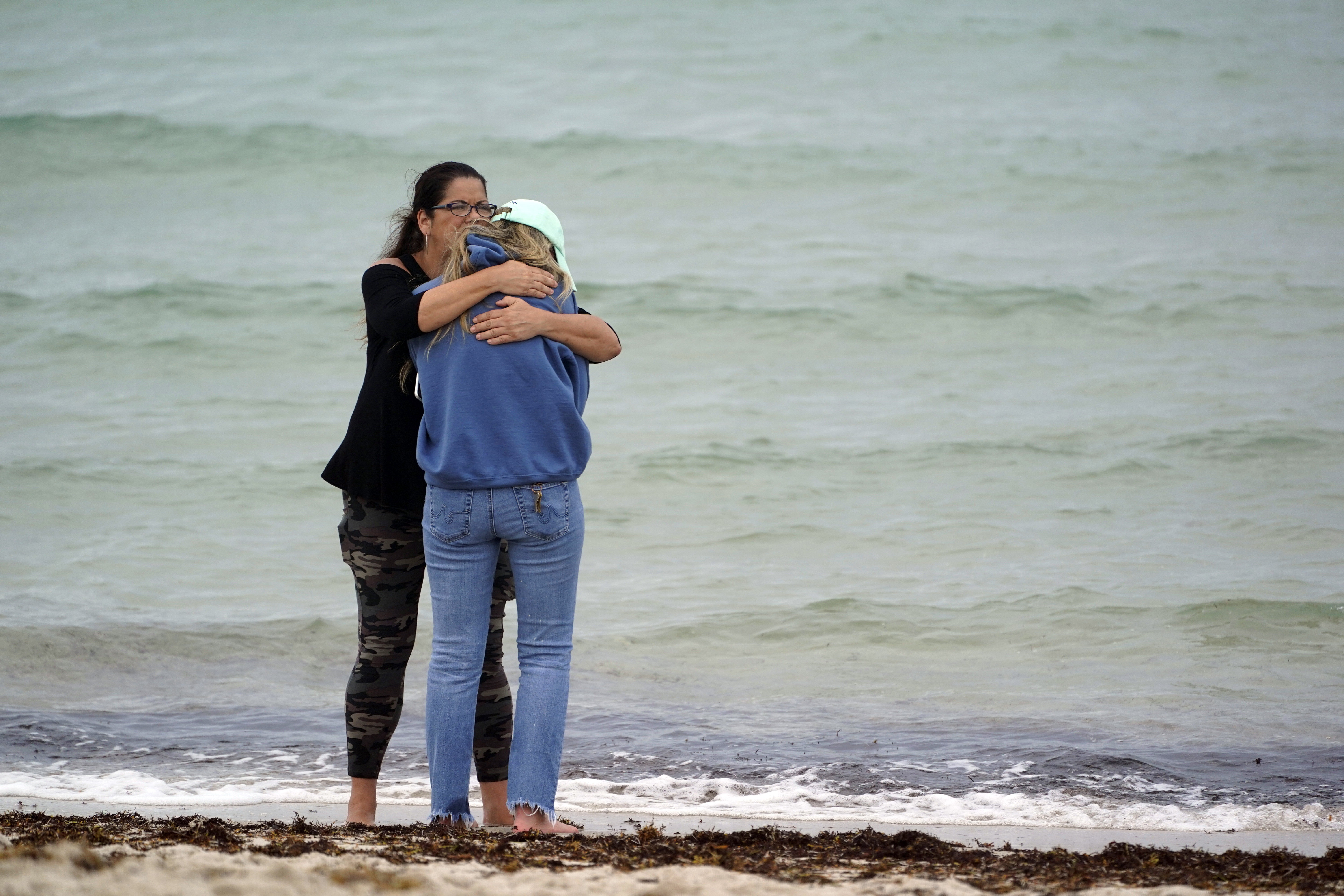 People console each other near the site of a partially collapsed building, June 24, 2021, in Surfside, Florida. A wing of a 12-story beachfront condo building collapsed with a roar in a town outside Miami early Thursday, trapping residents in rubble and twisted metal.