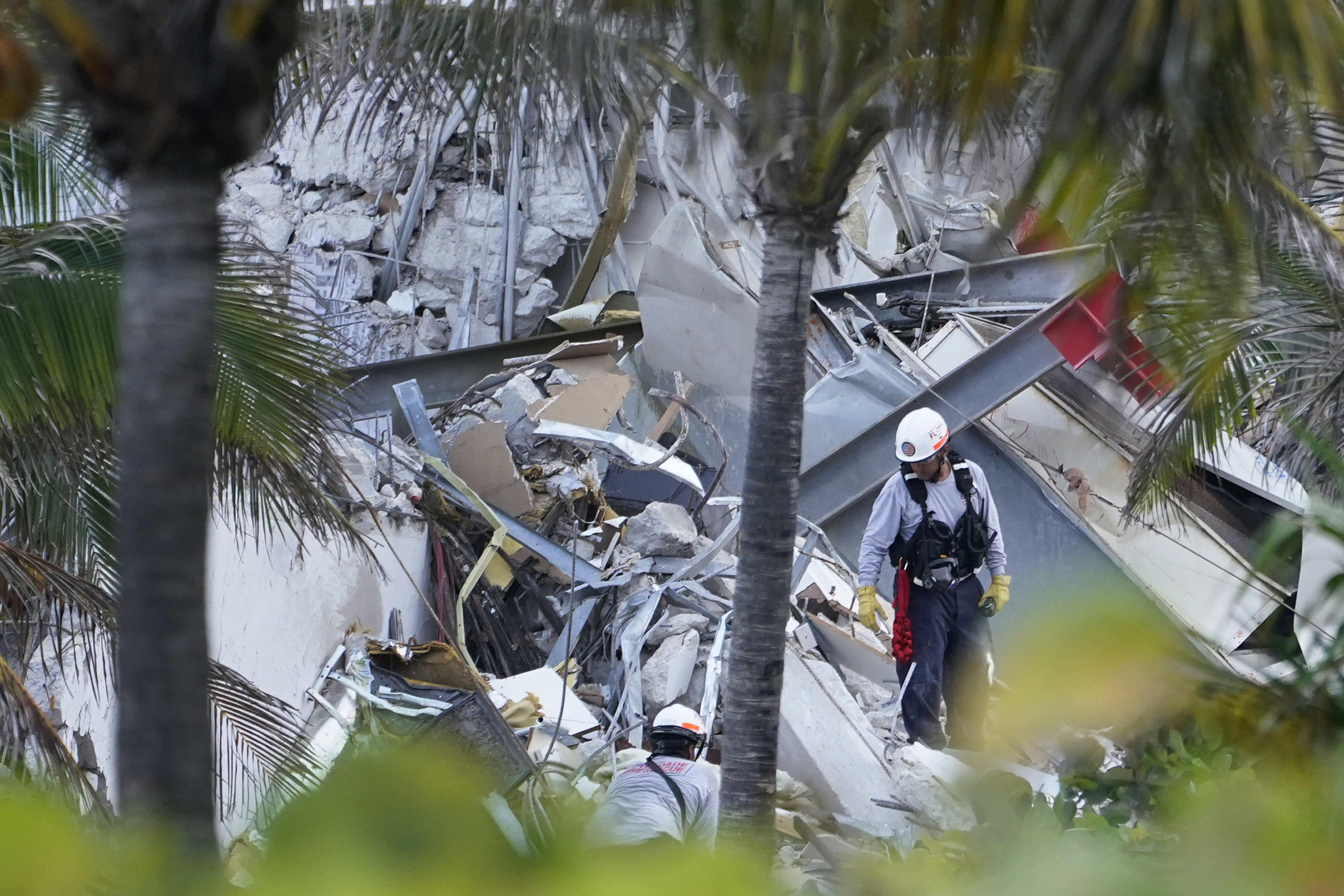 Rescue workers walk among the rubble where part of a 12-story beachfront condo building collapsed, Thursday, June 24, 2021, in Surfside, Florida.