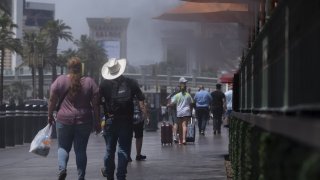 Pedestrians walk past misters along the Strip in Las Vegas, Nevada, U.S., on Wednesday, June 16, 2021. The searing weather marks the first heat-related stress tests of the year for U.S. power grids as a historic drought grips the western half of the nation.