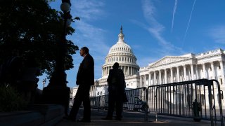 The U.S. Capitol is seen as people walking on the sidewalk with a fence, in Washington