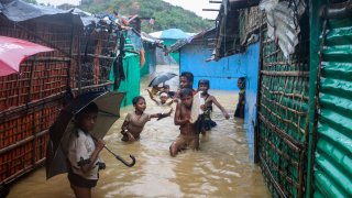 Rohingya refugee children play in flood waters at the Rohingya refugee cam