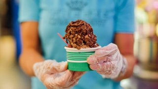 Close up of hands wearing protective gloves while holding a cup of ice cream