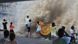 People watch high waves slapping the shore as typhoon In-Fa approaches