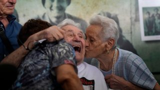 A 97 year old retired American soldier Martin Adler, center, receives a kiss by Mafalda, right, and Giuliana Naldi that he saved during a WWII, at Bologna's airport, Italy, Monday, Aug. 23, 2021. For more than seven decades, Martin Adler treasured a back-and-white photo of himself as a young soldier with a broad smile with three impeccably dressed Italian children he is credited with saving as the Nazis retreated northward in 1944. The 97-year-old World War II veteran met the three siblings -- now octogenarians themselves -- in person for the first time on Monday, eight months after a video reunion.