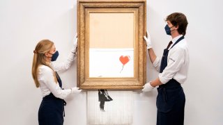 Art handlers at Sotheby's auction house hold Banksy's 'Love is in the Bin'