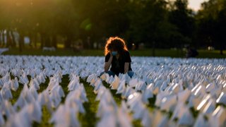 FILE - In this Sept. 17, 2021, file photo, Zoe Nassimoff, of Argentina, looks at white flags that are part of artist Suzanne Brennan Firstenberg's temporary art installation, "In America: Remember," in remembrance of Americans who have died of COVID-19, on the National Mall in Washington. Nassimoff's grandparent who lived in Florida died from COVID-19.