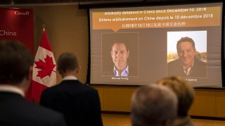 FILE - A video screen displays images of Canadians Michael Kovrig, left, and Michael Spavor at the Canadian Embassy in Beijing, Aug. 11, 2021. Kovrig and Spavor were released, along with Huawei executive Meng Wanzhou, in a three-way deal with China, Canada and the U.S., on Sept. 24, 2021.