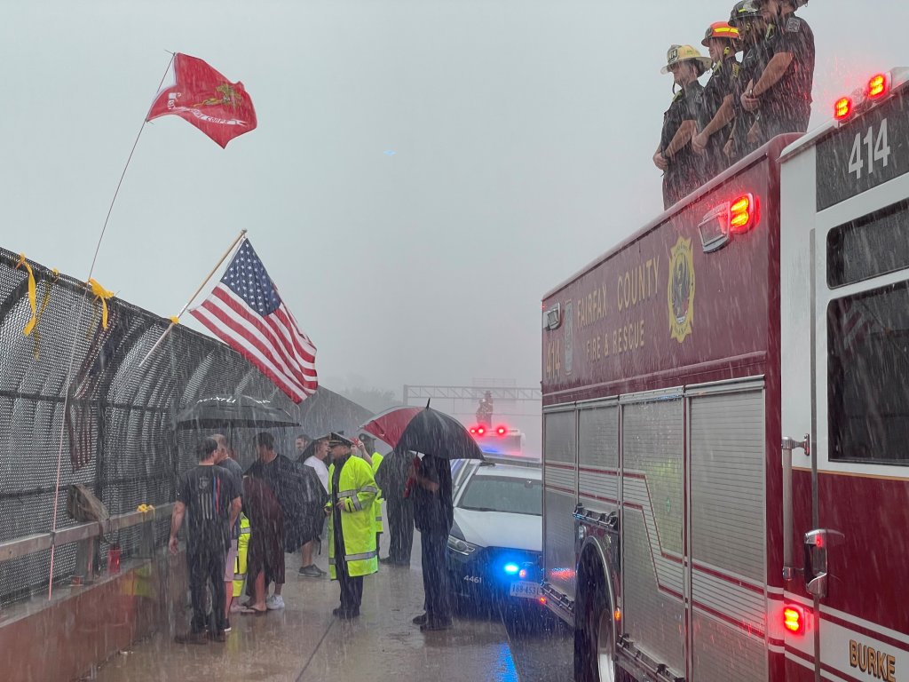 Fairfax firefighters and onlookers saluted the procession for a fallen soldier as the storm moved through Annandale.