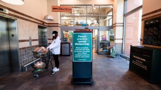 UNITED STATES – APRIL 11: A shopper wearing a face mask lstand next to the social distancing sign as she complete her Easter shopping at Harris Teeter grocery store in Washington on Saturday, April 11, 2020. (Photo By Bill Clark/CQ-Roll Call, Inc via Getty Images)