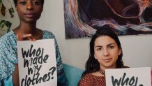 two women holding who made my clothes sign