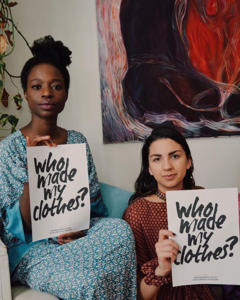 two women holding who made my clothes sign