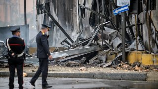 Carabinieri officers stand on the site of a plane crash, in San Donato Milanese suburb of Milan, Italy