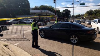 Officers allow a police vehicle to pass under yellow crime scene tape on a street in front of the post office in Memphis. Police said they are investigating a shooting at the post office in Tennessee.