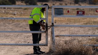 A security guard manning the entrance to the Bonanza Creek Ranch film set locks the gate after turning away workers who came to pick up equipment in Santa Fe, N.M., Monday, Oct. 25, 2021. A camera operator told authorities that Alec Baldwin had been careful with weapons on the set of the film "Rust." Baldwin shot and killed a cinematographer with a gun he'd been told was safe to use, court records released Sunday show.