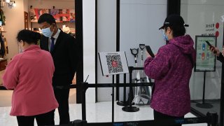 People scan a QR health code as a preventive measure against the Covid-19 coronavirus, before entering a shopping mall in Beijing on November 2, 2021.