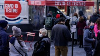 FILE – People wait in line at a COVID-19 testing site in Times Square, New York, Dec. 13, 2021.