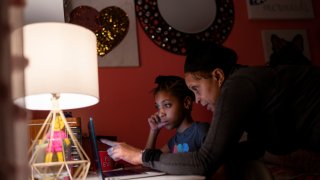 Abigail Schneider, 8, center, completes a level of her learning game with her mother April in her bedroom