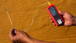 Vivek Shandas, a professor of climate adaptation at Portland State University, takes a temperature reading of almost 106 degrees in downtown Portland, Ore